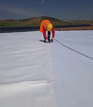 Nonwoven geotextile being laid and jointed on site